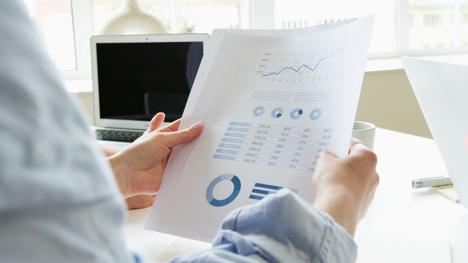 Dirigeant examinant un tableau de financement avec graphiques, devis et maquette de projet.